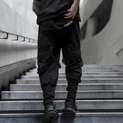Man wearing black urban techwear pants multiple pockets on both sides back